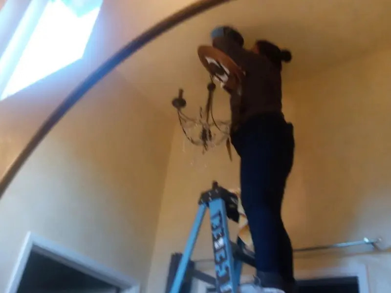 Electrician installing a chandelier in a Corona residence